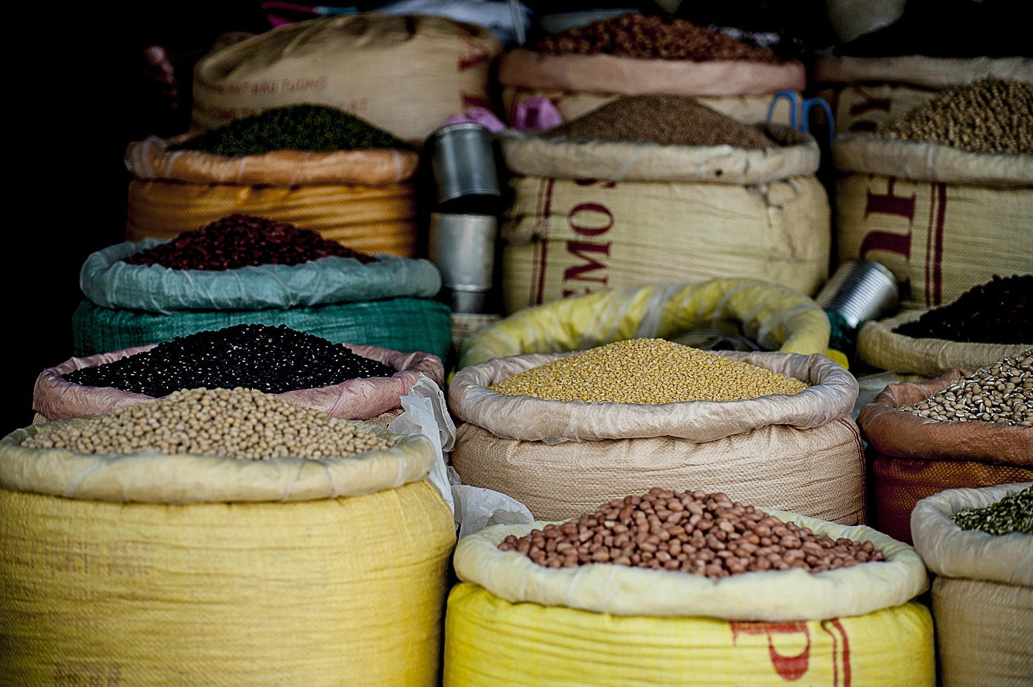 Vibrant market display of diverse, fresh legumes and grains in natural sacks.