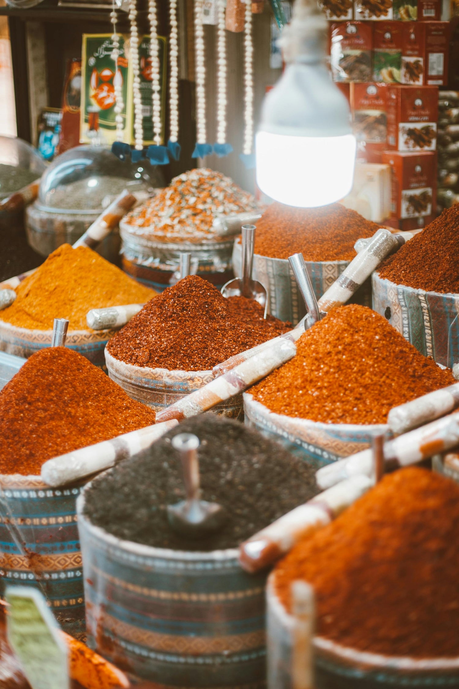 Vibrant collection of aromatic spices: red chilies, lentils, cinnamon sticks, and beans in white sacks.